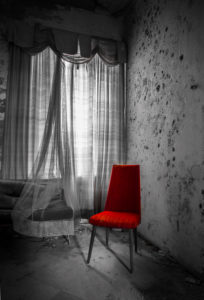 empty red chair by the window in an abandoned house empty red chair by the window in an abandoned house